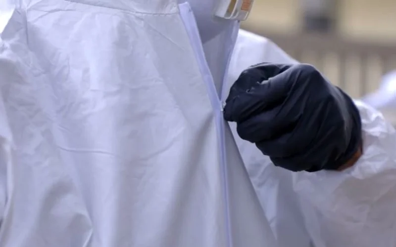 Mold remediation technician zipping up a protective suit before starting work