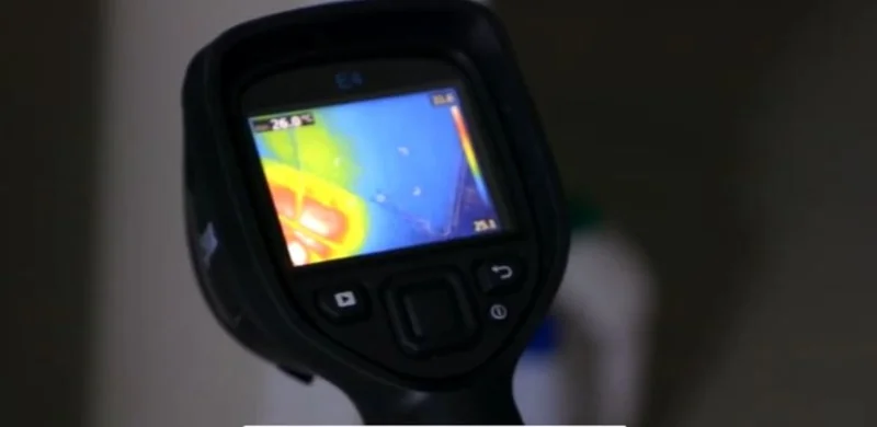 Thermal imaging camera showing a cold, damp spot on a wall during a moisture inspection